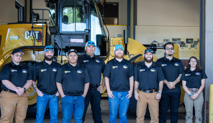 Team photo infront of a CAT tractor