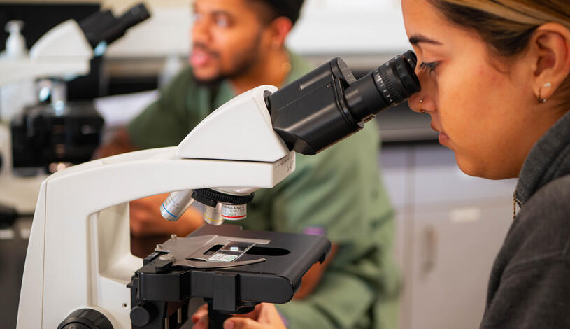 Photo of a student in biology class looking in microscope