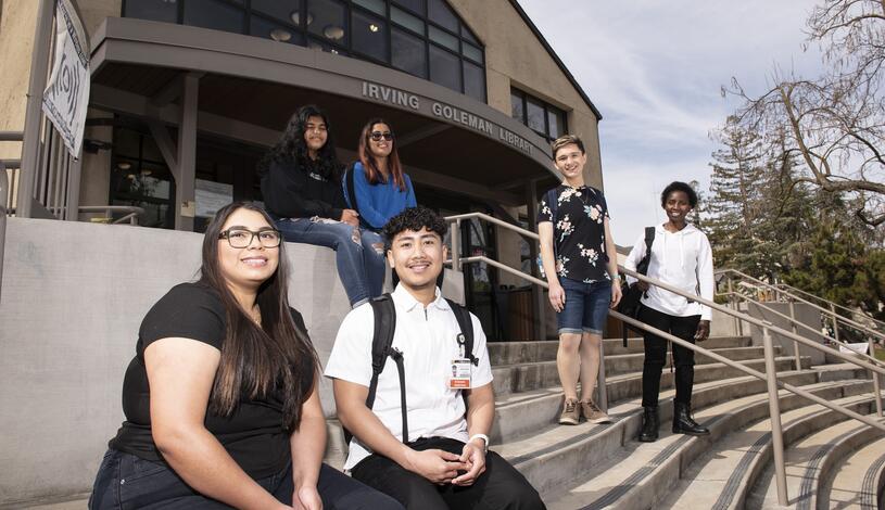 Photo of students sitting on the steps in front of Goleman Library