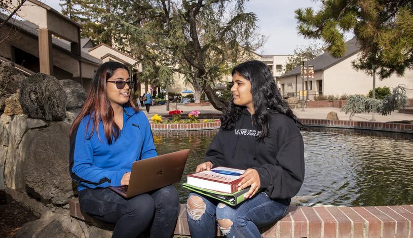 Photo of two students sitting at the koi pond