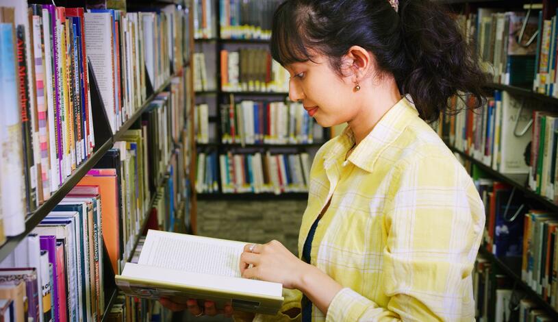 Photo of a student flipping through a book at Goleman Library