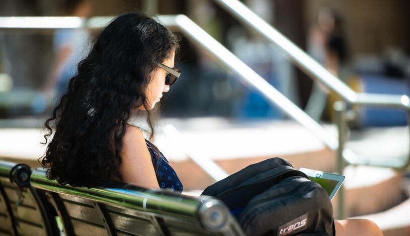 Photo of a student using laptop on bench