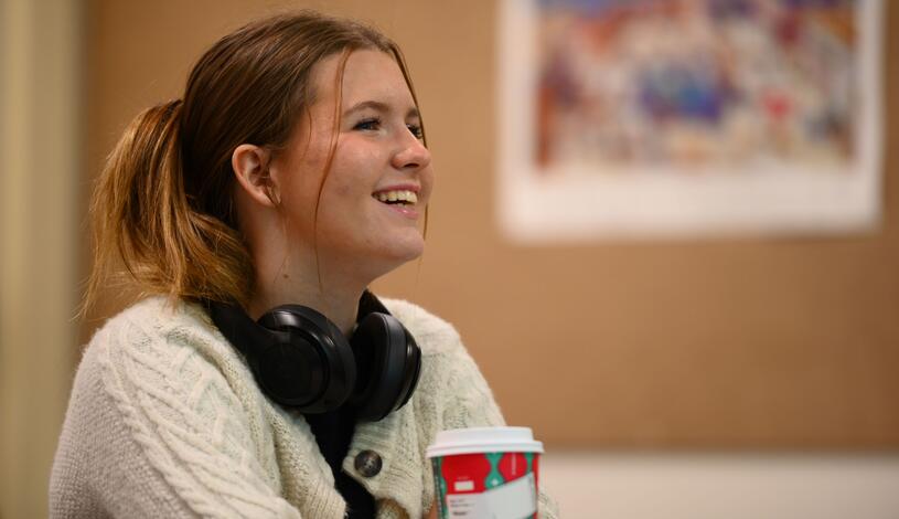 A student sitting down and smiling in a classroom.