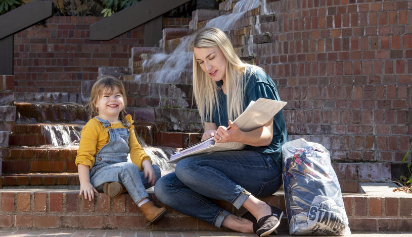 Parent and child sitting outside with books