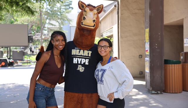 Two students pose with Fierce the Mustang for a photo