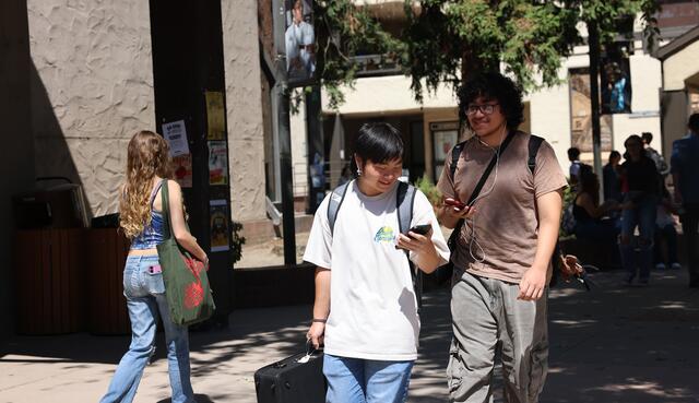 A student checks their phone while walking through campus