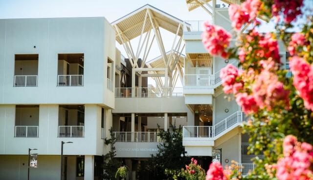 A photo of the Science and Math Building with beautiful blossoms in the foreground