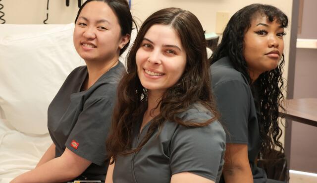 Photo of three students learning how to be nursing assistants 