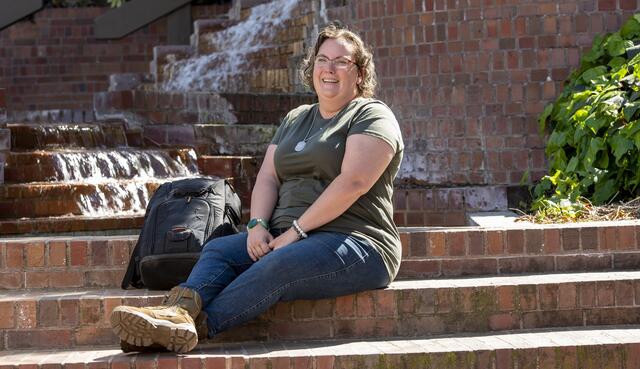 Photo of a student sitting on steps by Budd fountain