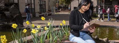 Photo of a student journaling next to the koi pond