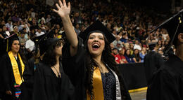 A Delta College graduate waves to her family