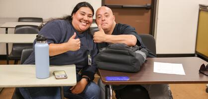 A DSPS student smiles during class and gives a thumbs up