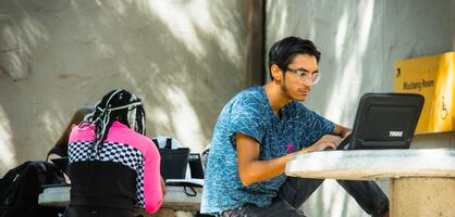 Photo of a student sitting at a table using laptop