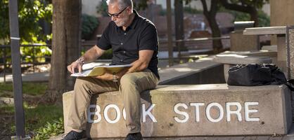 Student reading book in front of Bookstore