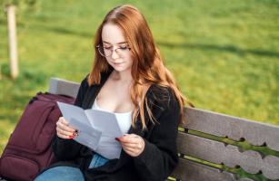 Student reading paper on a bench