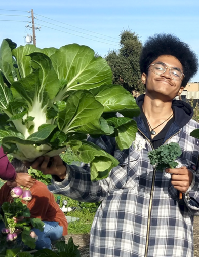 Student holding large green plant and smiling