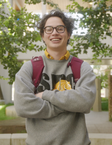 Student smiling with arms crossed wearing backpack