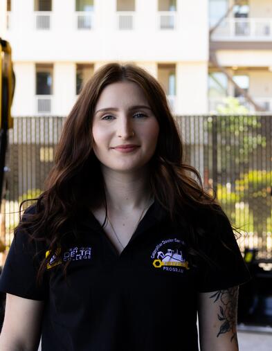 Student standing in front of Caterpillar machine/equipment