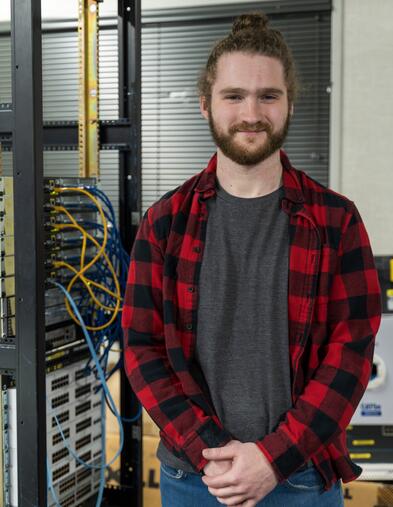 Student standing in front of CISCO equipment smiling