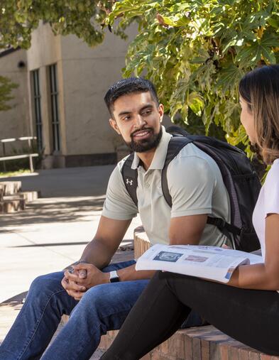 Two students sitting on steps talking to one another