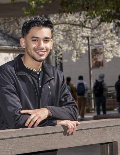 Student leaning on bridge and smiling