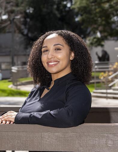 Student leaning on bridge and smiling
