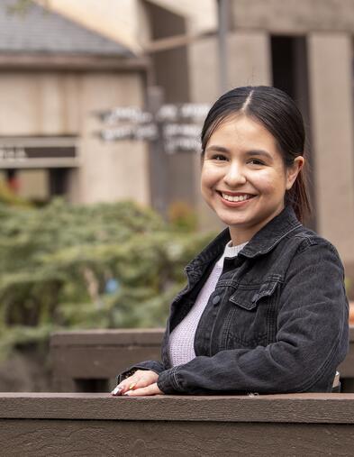 Student leaning on bridge smiling