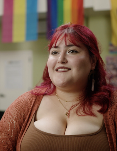 Student sitting in Pride Center with Pride flags behind them