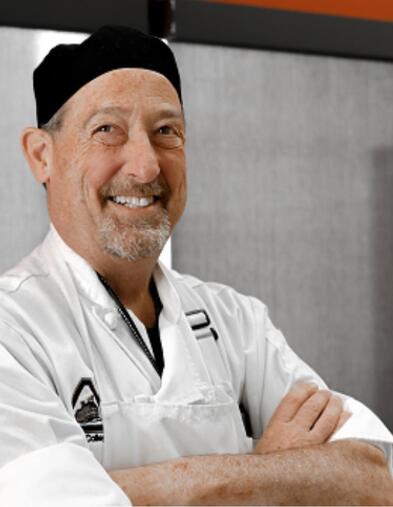 Portrait of student wearing Chef attire smiling with arms crossed