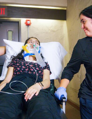 Two EMT students transporting a faux patient on a medical bed