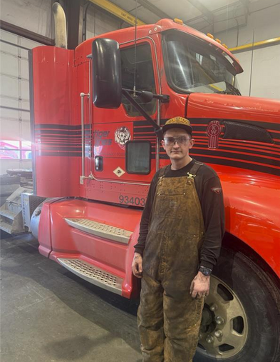 Student standing in front of red truck