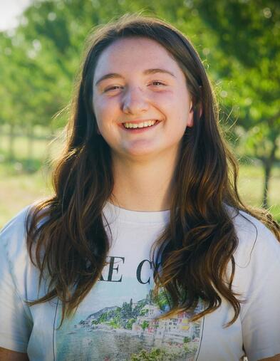 An agriculture student stands in an almond orchard